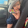 toddler, child, hat, cowboy_hat, toy, remote_control, car_seat, vehicle_interior, snacks, bag, blue_clothing, curious, seat, patterned_fabric, young_child, indoors, portrait, baby, cute, holding