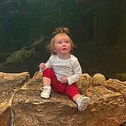 Stormie joined the competition — help win amazing prizes! toddler, child, rock, sitting, curious, looking_up, white_shirt, red_pants, polka_dot, shoes, pony_tail, indoor, stone, casual_clothing, young_child, expression, portrait, single_person, cute, festive