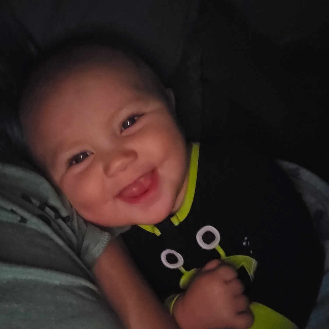 Johann is registered to the contest to win money with this photo: baby, bodypart, clothing, couch, cushion, face, finger, furniture, hand, happy, head, homedecor, laughing, mouth, newborn, person, photography, portrait, smile, t_shirt