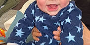 Martin participe au concours pour gagner de l'argent avec cette photo : baby, blue_onesie, cheerful, child, couch, cute, face, fingers, hands, happy, indoor, infant, living_room, person, sitting, skin, smiling, stars_pattern, warm_clothing, young