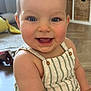 arm, baby, blue_eyes, cheeks, child, closeup, cute, face, happy, indoors, infant, person, portrait, romper, sitting, skin, smiling, striped_clothing, toy, wooden_floor