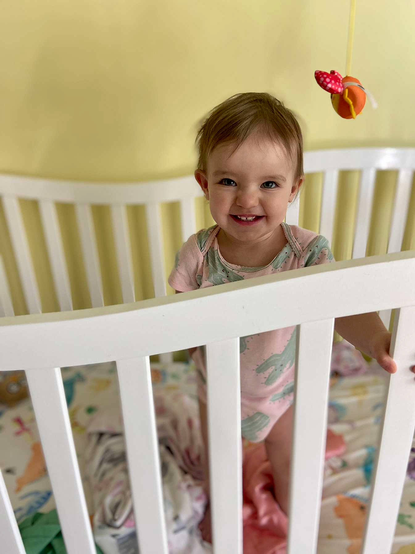Lilly is registered to the contest to win money with this photo: baby_safety, baby_toddler_clothing, bed, cradle, furniture, happy, infant_bed, joy, mammal, nursery, person, pink, product, skin, sleeve, smile, t_shirt, table, toddler, vertebrate
