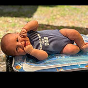 Emmanuel joined the competition — help win amazing prizes! baby, infant, smiling, onesie, striped_clothing, lying_down, outdoor, inflatable, pool_float, baby_clothing, cute, child, happy, skin, face, hand, summer, sunlight, playful, portrait