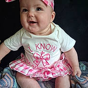 Addilynn is registered to the contest to win money with this photo: baby, child, smiling, headband, pink, white, clothing, sitting, blanket, cute, happy, face, cheerful, toddler, skirt, indoor, portrait, person, infant, bright