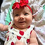 Aubree is registered to the contest to win money with this photo: baby, infant, smile, red_bow, headband, strawberry_pattern, dress, arm, hand, skin, face, eyes, blanket, soft_texture, close_up, happy, cute, child, indoors, portrait
