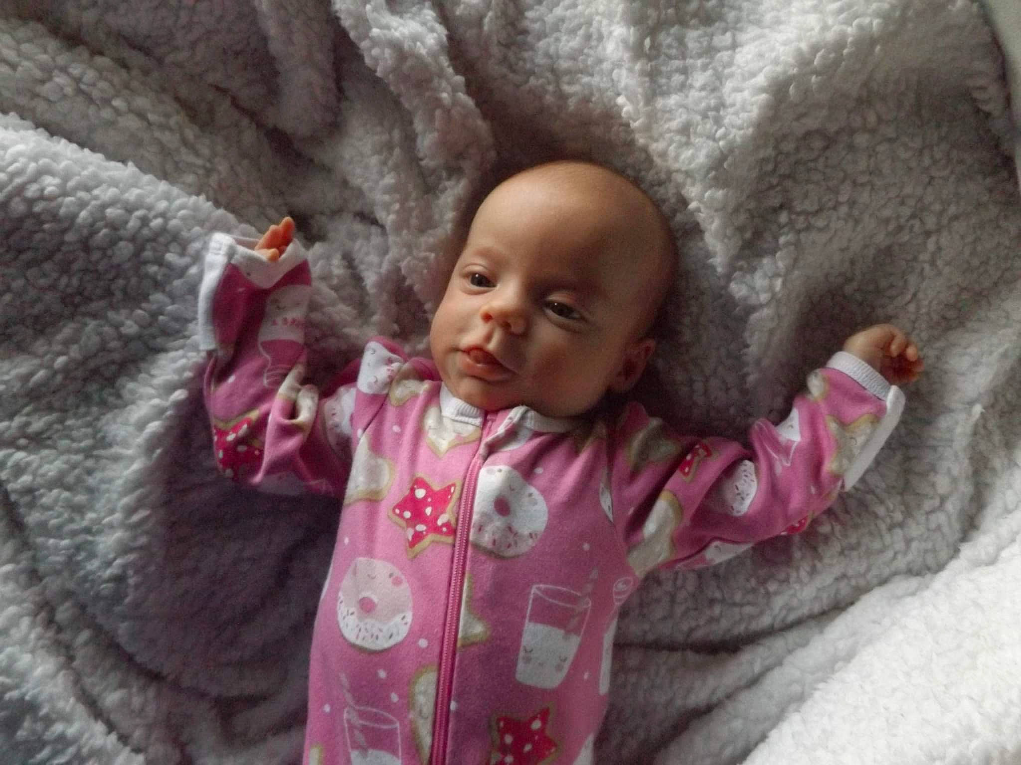 Lilith is registered to the contest to win money with this photo: baby, baby_toddler_clothing, cheek, child, face, freezing, fun, fur, gesture, happy, lip, magenta, nose, person, pink, rock, skin, smile, toddler, tree