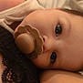 baby, pacifier, close_up, face, infant, child, sleepwear, skin, eyes, lying_down, comfort, soft_lighting, cute, portrait, indoors, young_child, head, expression, relaxation, warm