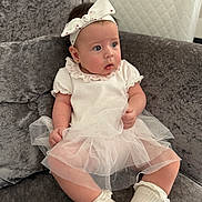 Emilia joined the competition — help win amazing prizes! baby, child, infant, dress, tulle, headband, bow, socks, couch, sofa, furniture, indoor, portrait, cute, curious, person, seated, white, soft_lighting, plush