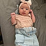 Emilia joined the competition — help win amazing prizes! baby, infant, headband, bow, pink_clothing, denim_skirt, white_socks, lace_trim, lying_down, gray_bed, cute, portrait, child, looking_at_camera, raised_fist, indoor, soft_lighting, small_hands, adorable, face
