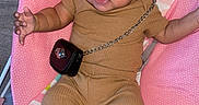 Jazara joined the competition — help win amazing prizes! baby, infant, child, pink_baby_seat, brown_outfit, fur_boots, small_purse, earrings, curly_hair, indoor, floor, playful, cute, person, seated, clothing, accessory, expression, adorable, young