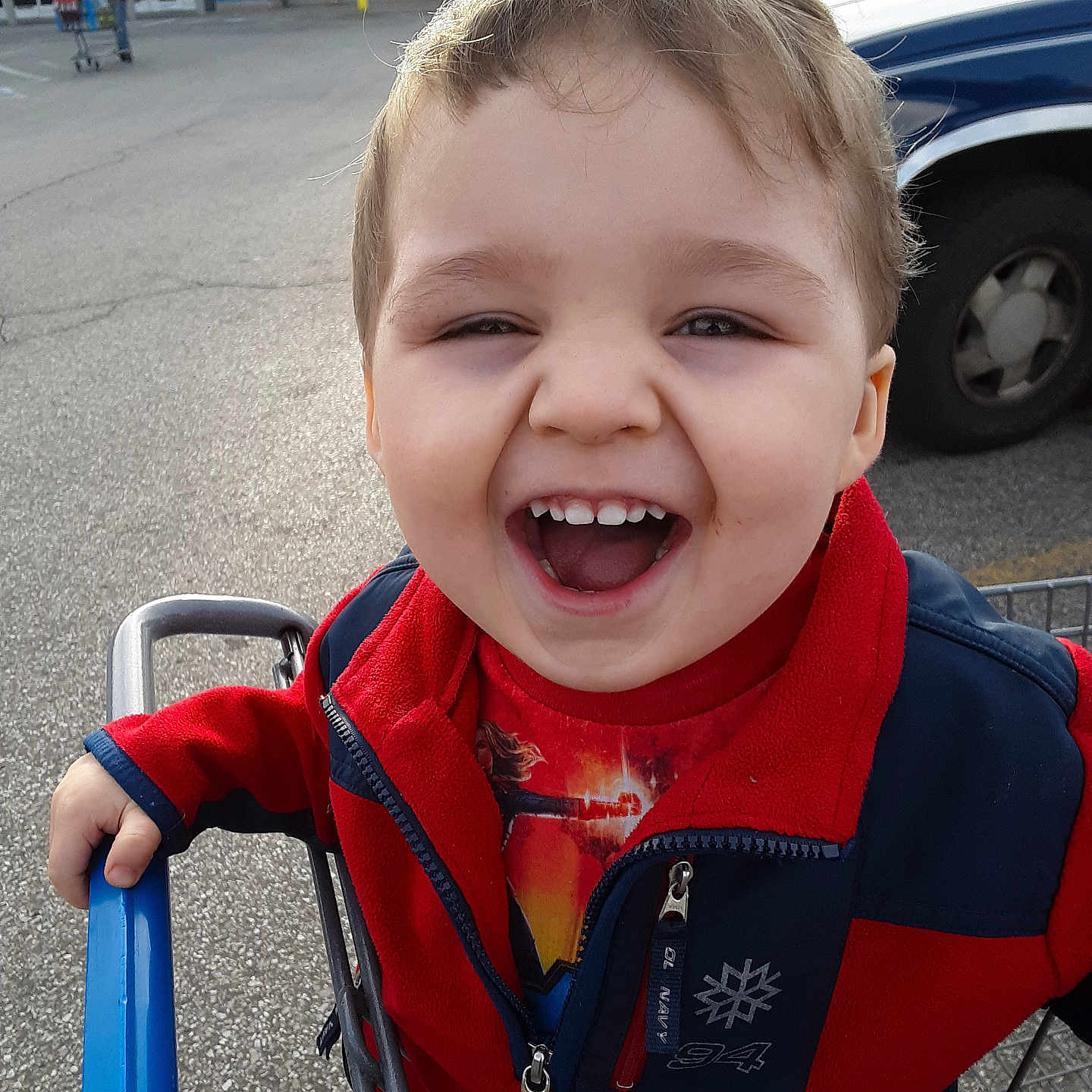 Robbie joined the competition — help win amazing prizes! child, toddler, smiling, shopping_cart, red_jacket, outdoor, parking_lot, vehicle, grocery_store, happy, face, person, casual_clothing, daylight, retail, playful, young_child, expression, holding, fun