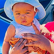 Lïam a rejoint le concours — aidez-le/la à gagner de superbes lots ! baby, child, hat, sun_hat, white_clothing, adult_hand, person, outdoor, car, blue_car, red_shirt, skin, portrait, holding, summer, sunlight, expression, cute, infant, people