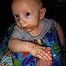 baby, blue_eyes, child, close_up, colorful_baby_seat, curious_expression, food_smudges, foot, gray_shirt, hand, indoor, infant, messy_face, person, playful, portrait, sea_creatures, sitting, skin, young_child