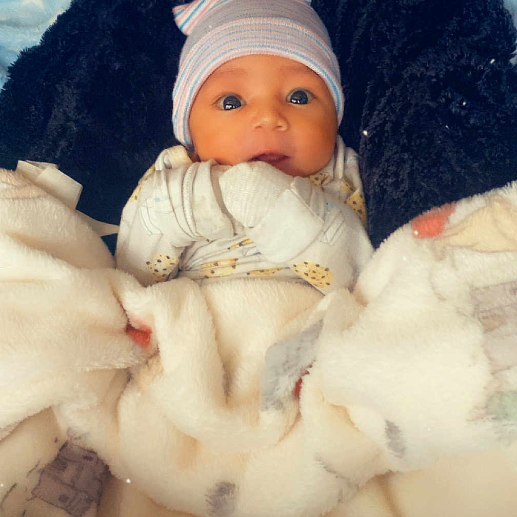 Naisaiah joined the competition — help win amazing prizes! baby, blanket, hat, face, infant, cozy, cute, wrapped, clothing, warm, bed, lying_down, soft, newborn, person, portrait, indoors, baby_clothes, gloves, expression
