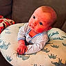 Tatum is registered to the contest to win money with this photo: baby, infant, drool, pillow, elephant_pattern, striped_clothing, couch, indoor, child, cute, portrait, hands, face, curious, soft_furniture, young_child, seated, home, resting, casual