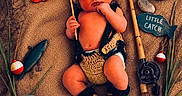 Tatum is registered to the contest to win money with this photo: baby, infant, sleeping, fishing, crocheted_clothing, hat, booties, fishing_rod, basket, wooden_sign, toy_fish, rocks, grass, fishing_net, bucket, props, cute, child, portrait, resting