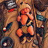 baby, infant, sleeping, fishing, crocheted_clothing, hat, booties, fishing_rod, basket, wooden_sign, toy_fish, rocks, grass, fishing_net, bucket, props, cute, child, portrait, resting