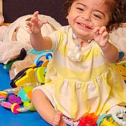 Athena joined the competition — help win amazing prizes! child, toddler, smiling, curly_hair, yellow_dress, sitting, toys, colorful, indoor, happy, playtime, baby_toys, floor_mat, cute, infant, reaching_out, person, young_child, joyful, play