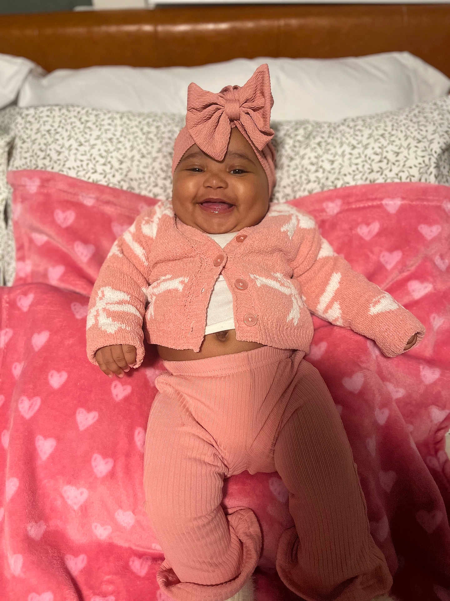 Brailee Beachum joined the competition — help win amazing prizes! baby, infant, smile, headband, bow, pink_blanket, heart_pattern, cardigan, pants, bed, pillow, cozy, happy, cute, portrait, lying_down, hand, soft_toy_style, clothing, nursery