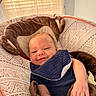 baby, infant, smiling, bib, baby_seat, comfort, indoor, patterned_fabric, child, happy, face, cute, relaxed, clothing, arm, hand, seatbelt, soft_toys, window, daylight