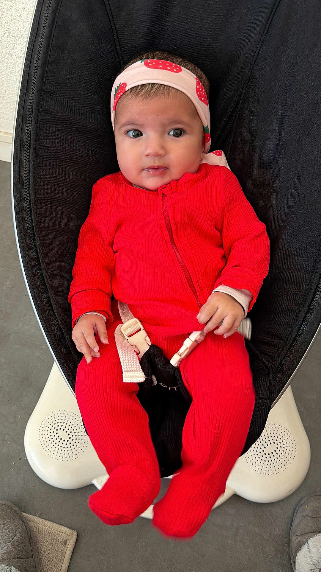 Belsame participe au concours pour gagner de l'argent avec cette photo : baby, infant, red_onesie, headband, strawberry_pattern, baby_rocker, buckle, indoor, floor, slippers, curious, seated, clothing, child, person, cute, portrait, hands, footwear, carpet