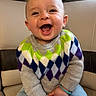 Jonas a rejoint le concours — aidez-le/la à gagner de superbes lots ! baby, child, smile, laughing, sweater, argyle, blue_pants, cushion, indoor, happy, cute, joyful, seated, face, person, infant, cozy, warm_clothing, chubby_cheeks, casual