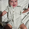 baby, infant, smile, happy, onesie, striped_clothing, blanket, soft_texture, face, arms, legs, cute, child, lying_down, indoors, person, newborn, joyful, expression, human