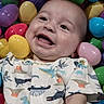 baby, smiling, face, child, dinosaur_print, easter_eggs, colorful, plastic_eggs, cute, happy, infant, playful, clothing, portrait, indoors, young_child, head, skin, eyes, mouth
