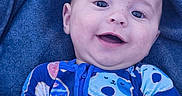 Oakley is registered to the contest to win money with this photo: baby, bear_pattern, blue_blanket, child, closeup, colorful_clothing, cute, donut_pattern, face, happy, indoor, infant, lying_down, onesie, playful, portrait, smiling, soft_texture, young_child, zipped_clothing
