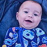Oakley is registered to the contest to win money with this photo: baby, child, smiling, face, blue_blanket, colorful_clothing, onesie, donut_pattern, bear_pattern, happy, portrait, infant, cute, closeup, soft_texture, lying_down, young_child, zipped_clothing, indoor, playful