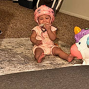Layla joined the competition — help win amazing prizes! baby, helmet, carpet, toy, unicorn, indoor, child, floor, cloth, pet_carrier, pink, crawling, cute, sitting, infant, home, play, protection, furniture, person