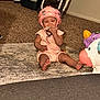 baby, helmet, carpet, toy, unicorn, indoor, child, floor, cloth, pet_carrier, pink, crawling, cute, sitting, infant, home, play, protection, furniture, person
