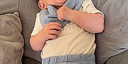 Arlo is registered to the contest to win money with this photo: baby, infant, smile, happy, couch, pillow, clothing, shorts, bib, skin, hand, face, legs, indoors, relaxing, cute, child, young, person, cozy
