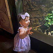 Mia joined the competition — help win amazing prizes! toddler, child, girl, purple_dress, headband, bow, smiling, waving, indoor, glass, greenery, carpet, standing, cute, happy, short_hair, footwear, crocs, portrait, curious