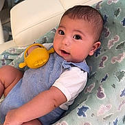 Andrew joined the competition — help win amazing prizes! baby, infant, child, cute, blue_romper, white_shirt, yellow_toy, blanket, animal_print, soft_texture, indoor, furniture, chair, smiling, portrait, closeup, skin, face, eyes, hand