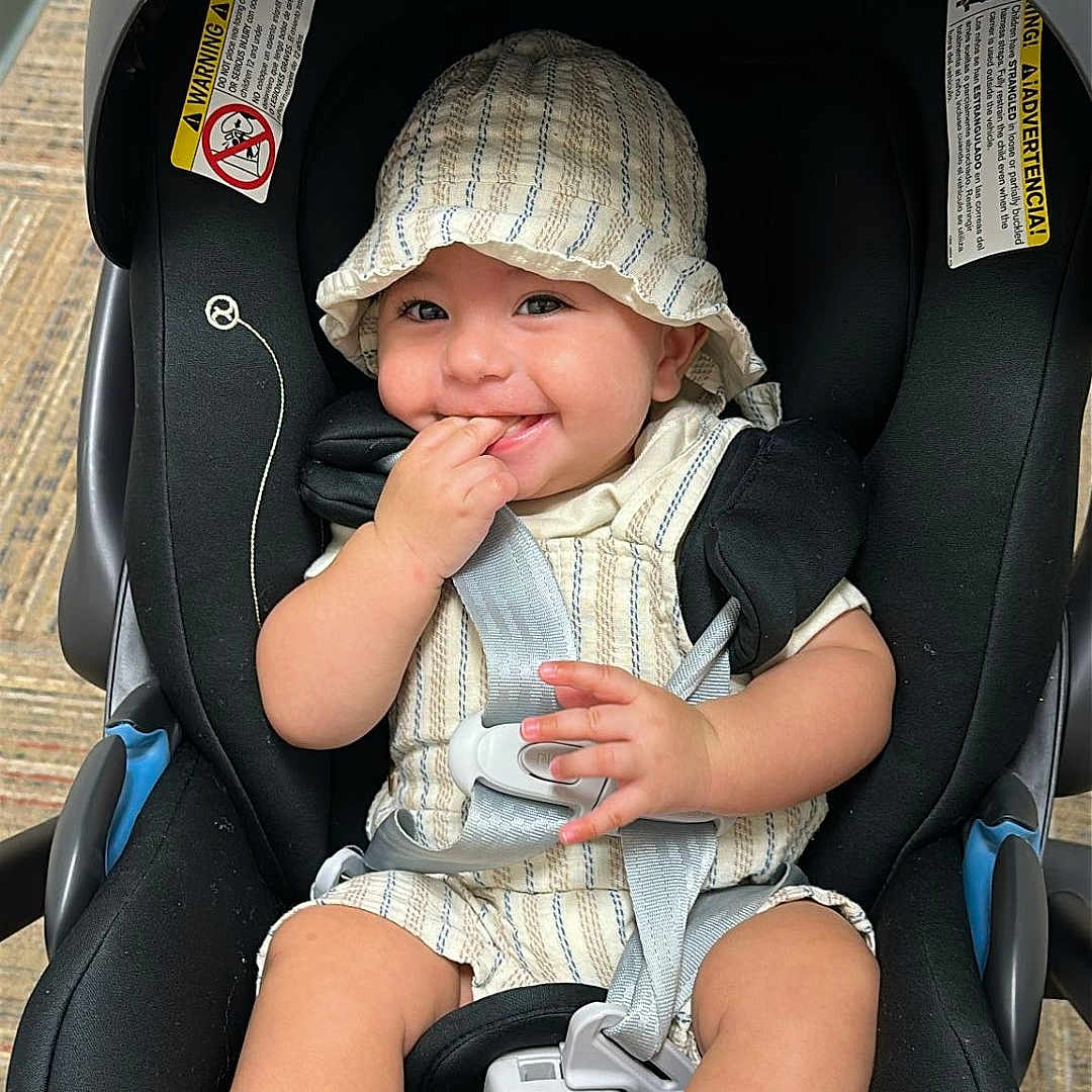 Andrew joined the competition — help win amazing prizes! baby, barefoot, car_seat, child, clothing, cute, expression, fingers, footwear, happy, hat, indoor, infant, person, playful, safety_harness, seat, sitting, smiling, stripes