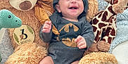 Andrew joined the competition — help win amazing prizes! baby, infant, smiling, batman_onesie, hooded_clothing, plush_toys, teddy_bear, giraffe_toy, dinosaur_toy, triceratops_toy, milestone_card, 3_months, blanket, socks, happy, cute, indoors, soft_toys, child, portrait