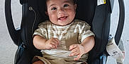 Andrew is registered to the contest to win money with this photo: baby, smiling, car_seat, striped_shirt, shorts, child, happy, infant, person, clothing, seatbelt, indoor, cute, young_child, baby_face, playful, hands, casual_wear, seat, adorable
