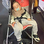 Nolann participe au concours pour gagner de l'argent avec cette photo : toddler, sleeping, stroller, pacifier, bib, sweatpants, shoes, child, indoor, wheel, footwear, clothing, baby, resting, person, young_child, casual_wear, seat, comfort, nap