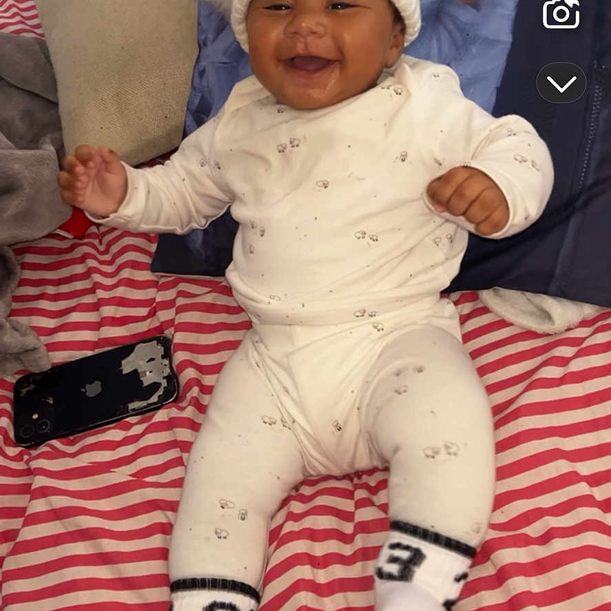 Drayton-Reign joined the competition — help win amazing prizes! baby, child, clothing, cozy, cute, happy, indoors, infant, person, phone, pillow, pom_poms, portrait, sitting, smiling, sock, soft_toys, striped_blanket, warm, white_hat