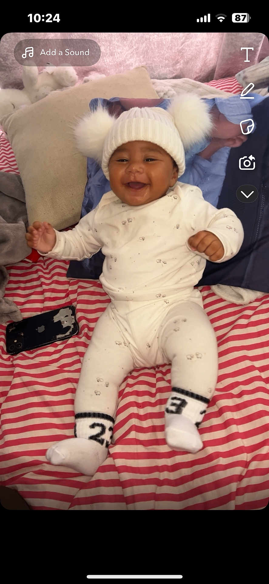 Drayton-Reign joined the competition — help win amazing prizes! baby, child, smiling, sitting, white_hat, pom_poms, striped_blanket, pillow, phone, indoors, cute, happy, cozy, clothing, sock, infant, person, portrait, soft_toys, warm