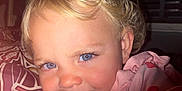 Kyra is registered to the contest to win money with this photo: toddler, child, face, blue_eyes, blonde_hair, portrait, pink_clothing, heart_pattern, close_up, indoor, lighting, shadow, cute, smile, young_child, person, warm_light, expression, hair, baby