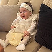 Yara participe au concours pour gagner de l'argent avec cette photo : baby, child, girl, couch, purse, headband, white_shoes, tights, dress, smiling, sitting, indoor, cushion, beige, black_cushion, cute, happy, small_bag, accessory, portrait