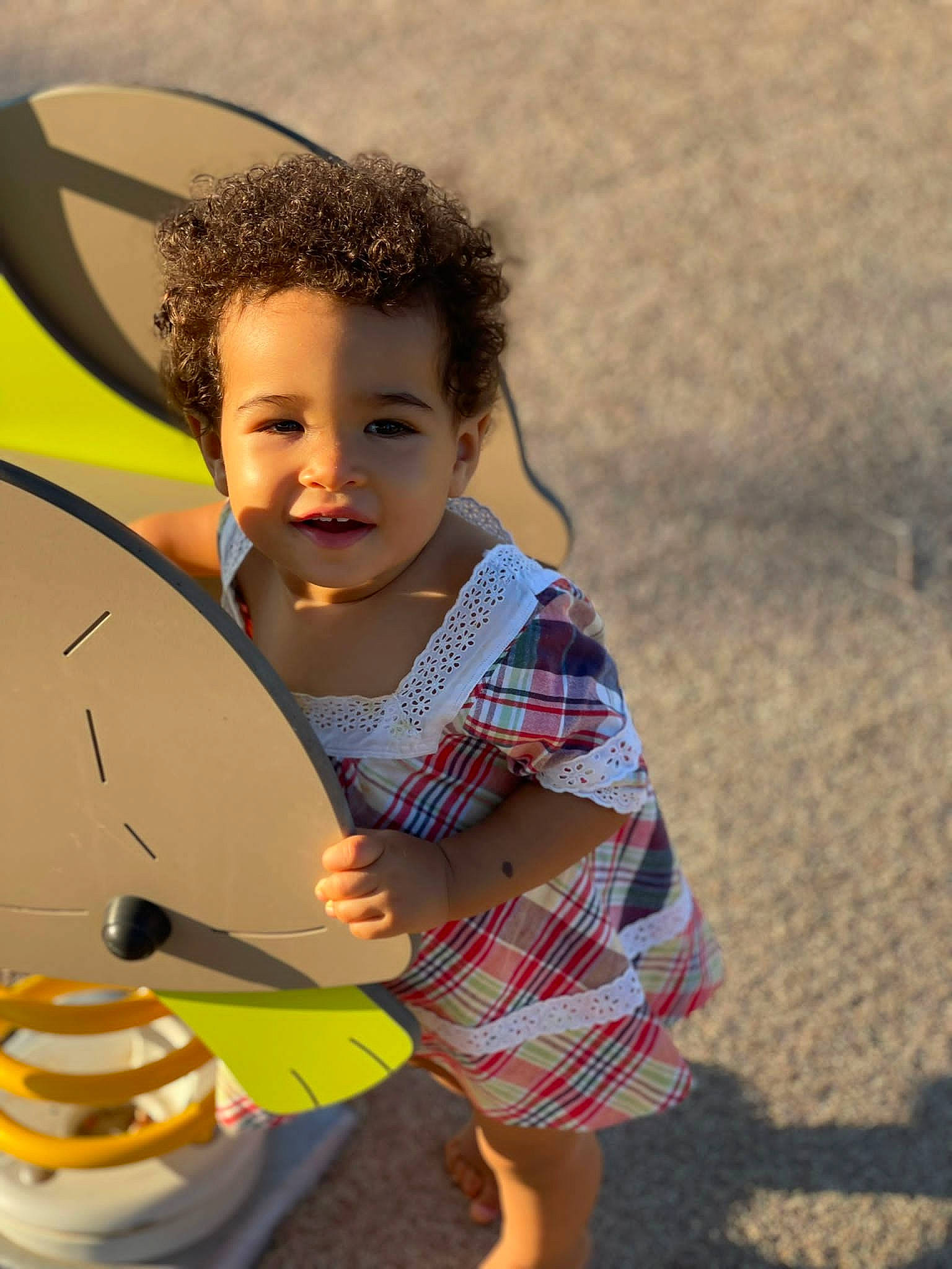 Nyah a rejoint le concours — aidez-le/la à gagner de superbes lots ! baby, child, facial_expression, fun, grass, happy, leisure, pattern, people, person, plaid, play, recreation, shorts, sitting, smile, t_shirt, tartan, toddler, umbrella