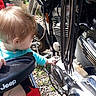 toddler, child, baby, motorcycle, engine, vehicle, outdoor, curious, reaching, turquoise_shirt, blond_hair, profile, portrait, machinery, chrome, metal, mechanic, sunlight, gravel, jeep