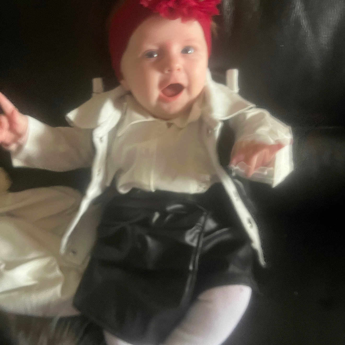 Emmylia a rejoint le concours — aidez-le/la à gagner de superbes lots ! baby, child, headband, flower, white_jacket, black_skirt, pointing, sitting, happy, indoor, person, clothing, cute, infant, portrait, smiling, young_child, fashion, red, dark_background
