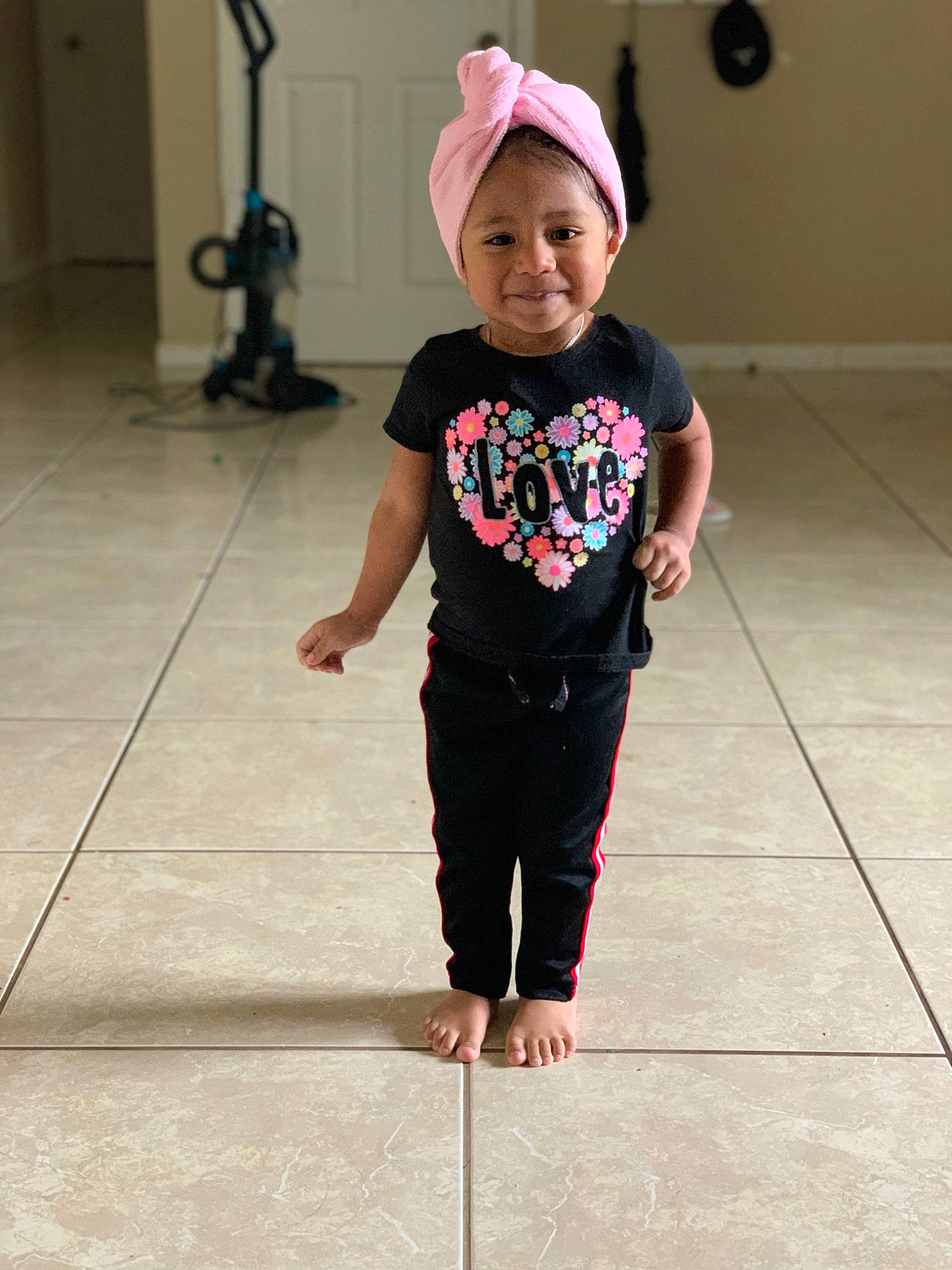 Tatiana is registered to the contest to win money with this photo: active_pants, baby, baby_toddler_clothing, barefoot, cap, child, door, face, flooring, fun, happy, human_leg, joy, magenta, pattern, person, sleeve, smile, sweatpant, t_shirt