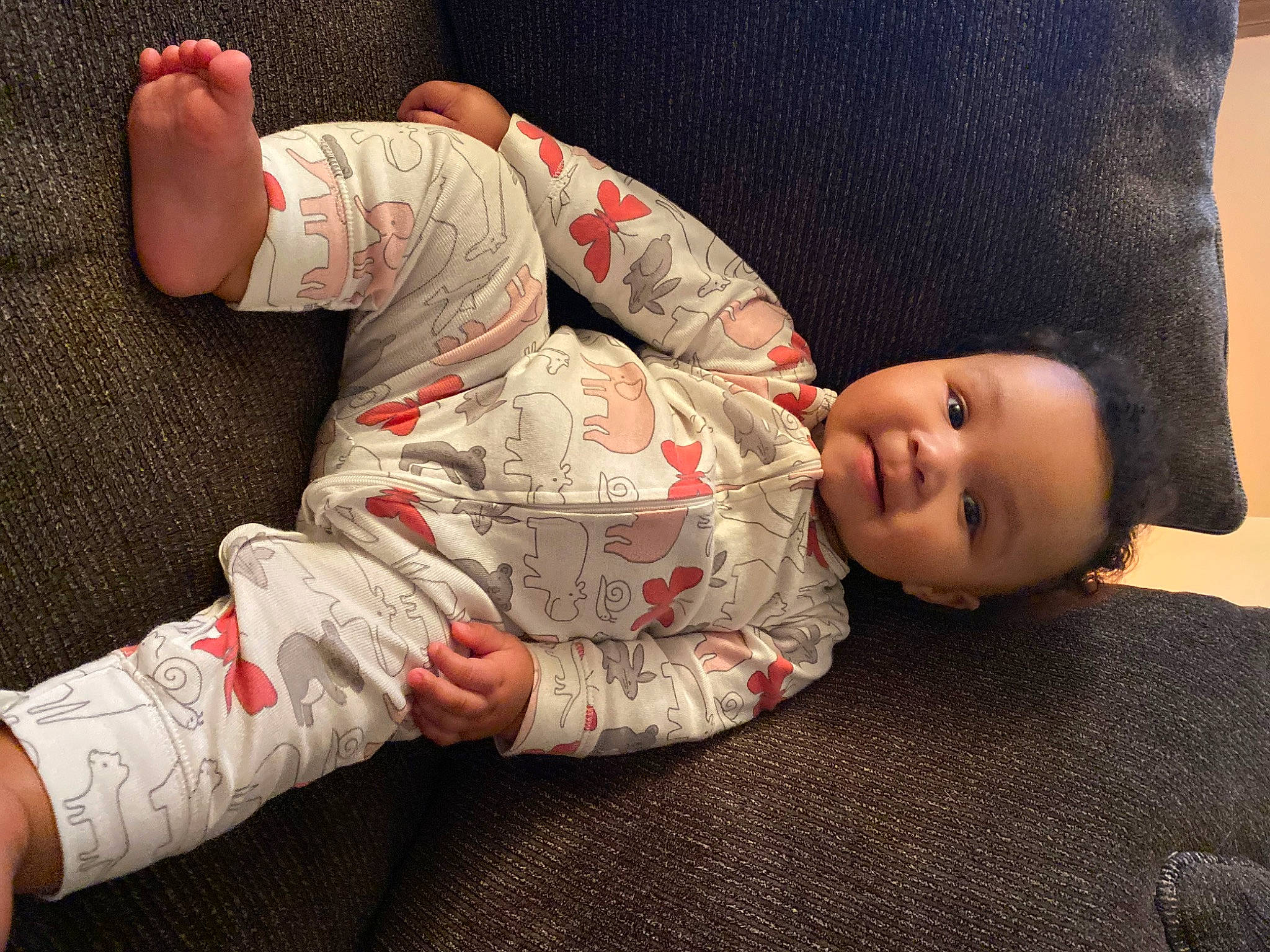 Averi is registered to the contest to win money with this photo: baby, baby_toddler_clothing, child, comfort, couch, elbow, finger, flooring, gesture, human_leg, knee, leg, mouth, person, skin, sleeve, smile, sock, thigh, toddler