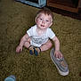 Waylon joined the competition — help win amazing prizes! baby, child, carpet, shoe, socks, indoor, furniture, cabinet, wood, floor, person, curious, blue_eyes, white_onesie, hand, foot, sitting, infant, room, casual