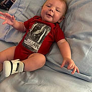 Waylon joined the competition — help win amazing prizes! baby, infant, red_onesie, sneakers, bed, pillow, smiling, happy, child, cute, skin, hand, footwear, clothing, indoors, relaxing, portrait, person, young_child, cozy